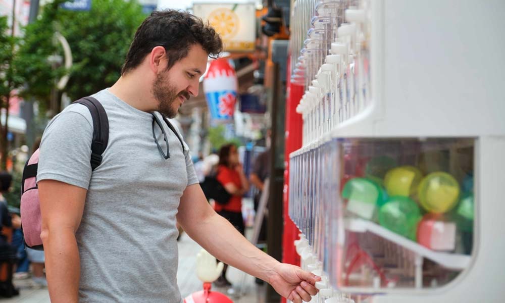 Un homme devant des machines gashapon à paris