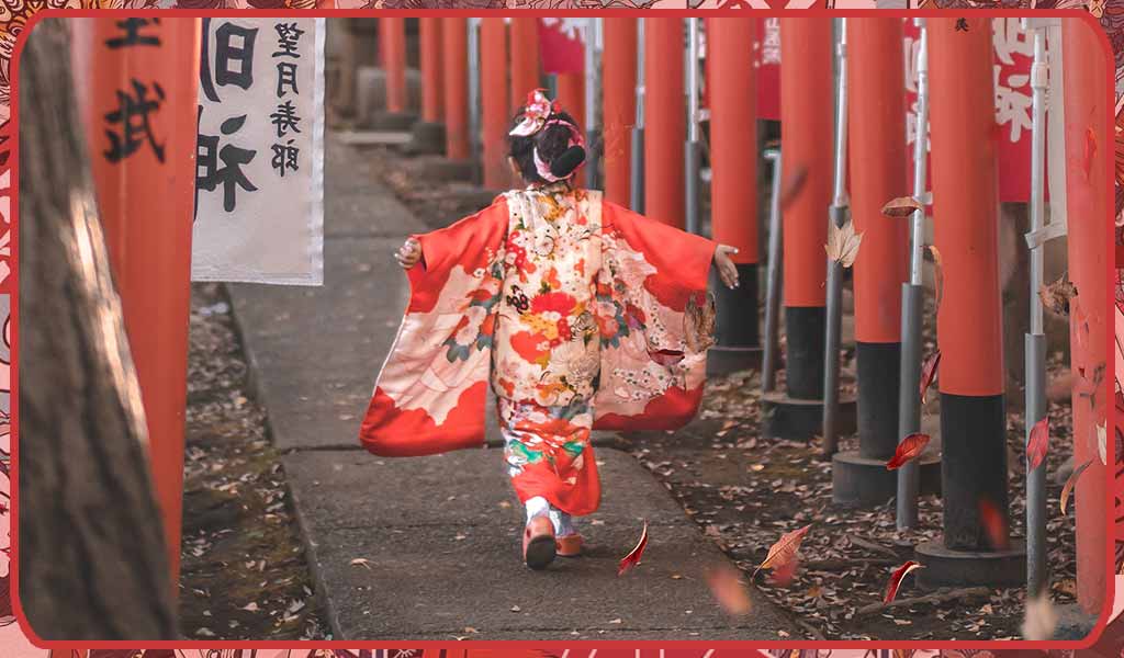 Un kimono japonais fille de couleur rouge porté dans un temple Shintho avec des portes Torrii rouges