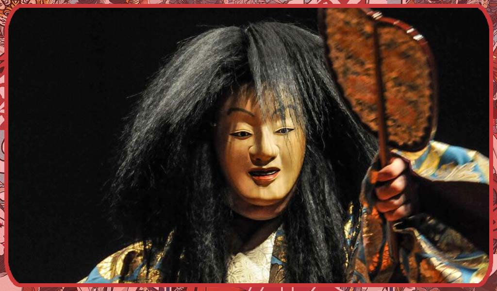 Une personne porte un masque theatre japonais no et un eventail uchiwa. Le masque a une perruque de cheveux noir