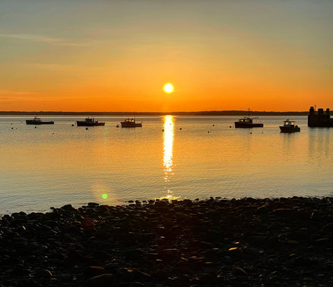 Sunrise over Penobscot Bay with orange sky and silhouettes of lobster boats
