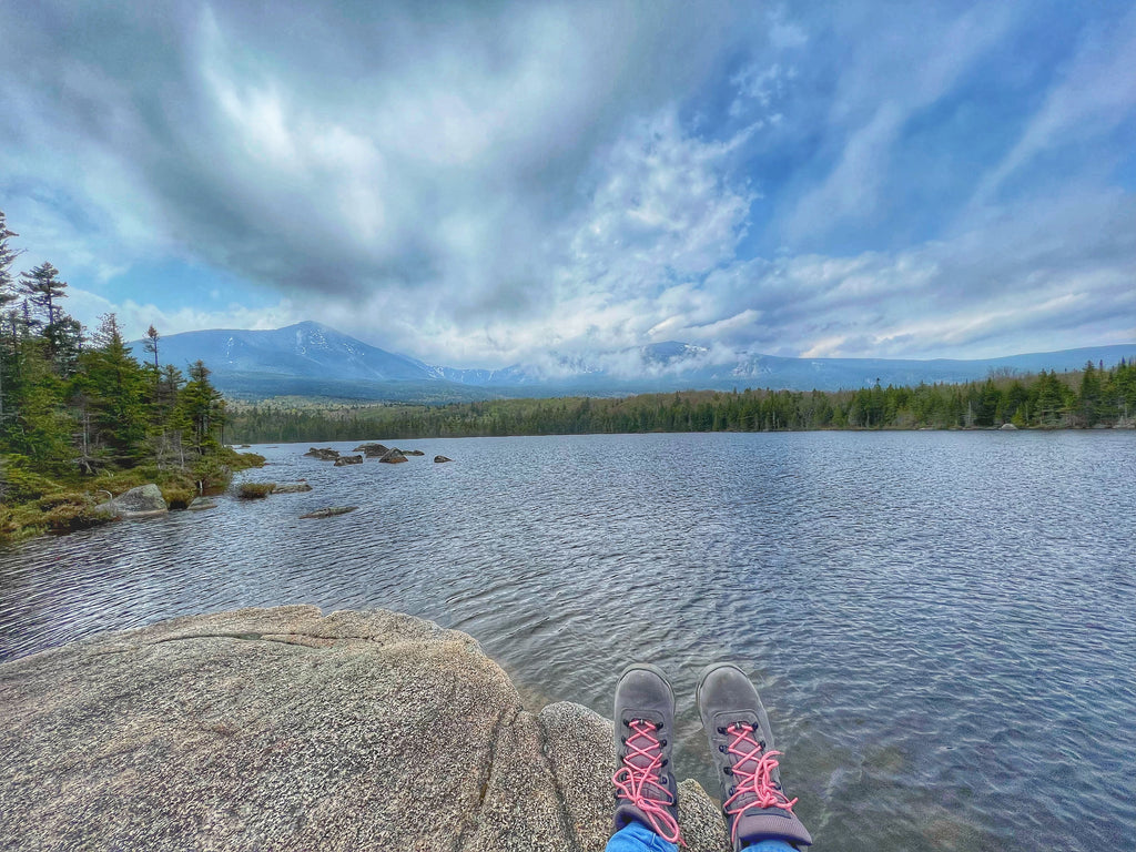 Sandy Stream Pond, person sitting on rock overlooking pond with mountains in background