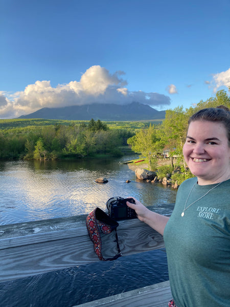 Woman standing on bridge looking at Katahdin with camera in hand