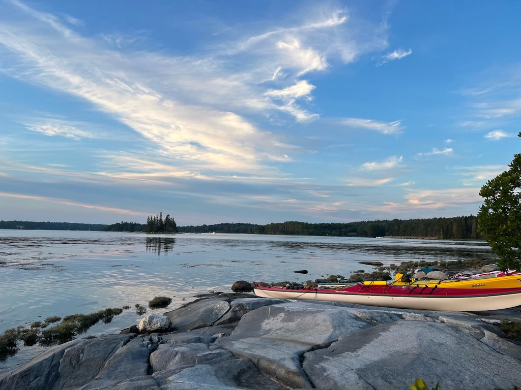 Overlooking coastal Maine, rocky shore with two kayaks with water and blue skies