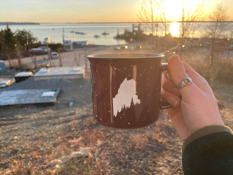 person holding up coffee mug looking over Lincolnville Ferry Terminal with sunrise