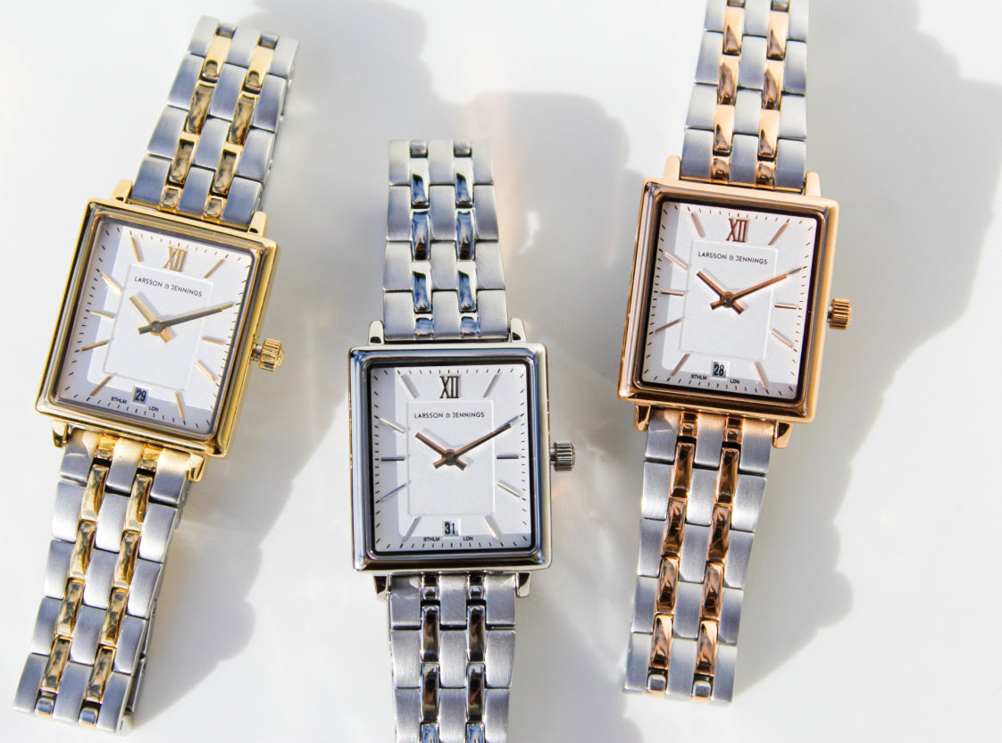 Three luxury wristwatches with metallic straps and rectangular faces in gold, silver, and rose gold.