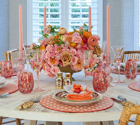 Kim Seybert tablescape, with the Basketweave Placemat, Sea Stone Napkin Ring, and Seersucker Napkin - all in hues of orange, pink, and coral