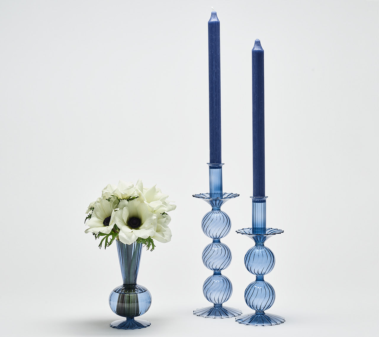 Blue glassware vase and candleholder centerpiece in mixed sizes styled with seasonal flowers