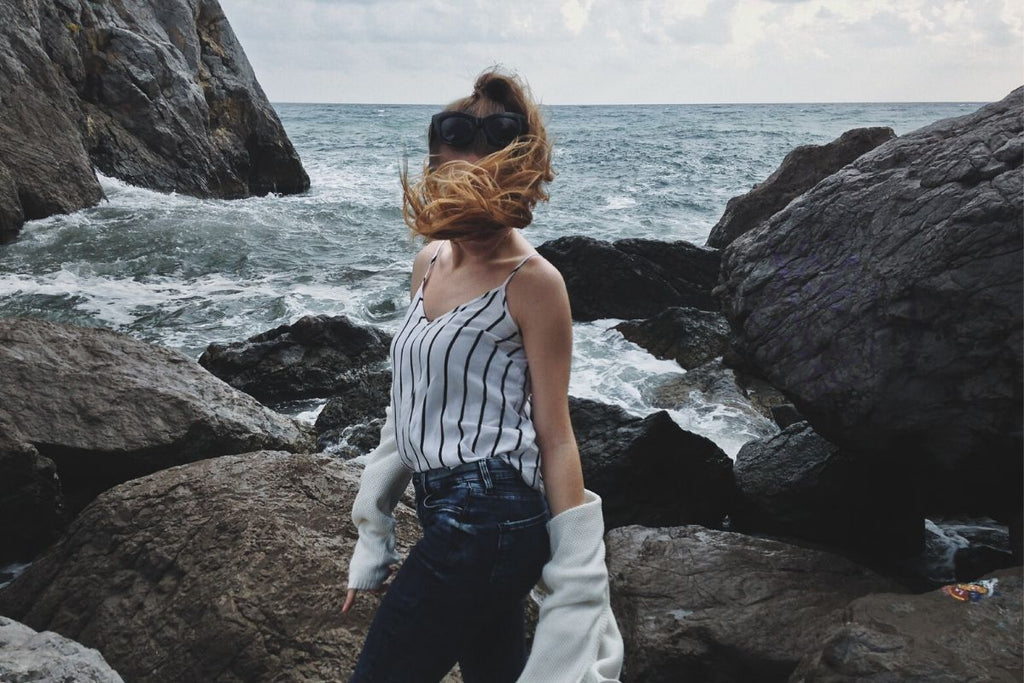 woman standing in front of sea with hair blowing