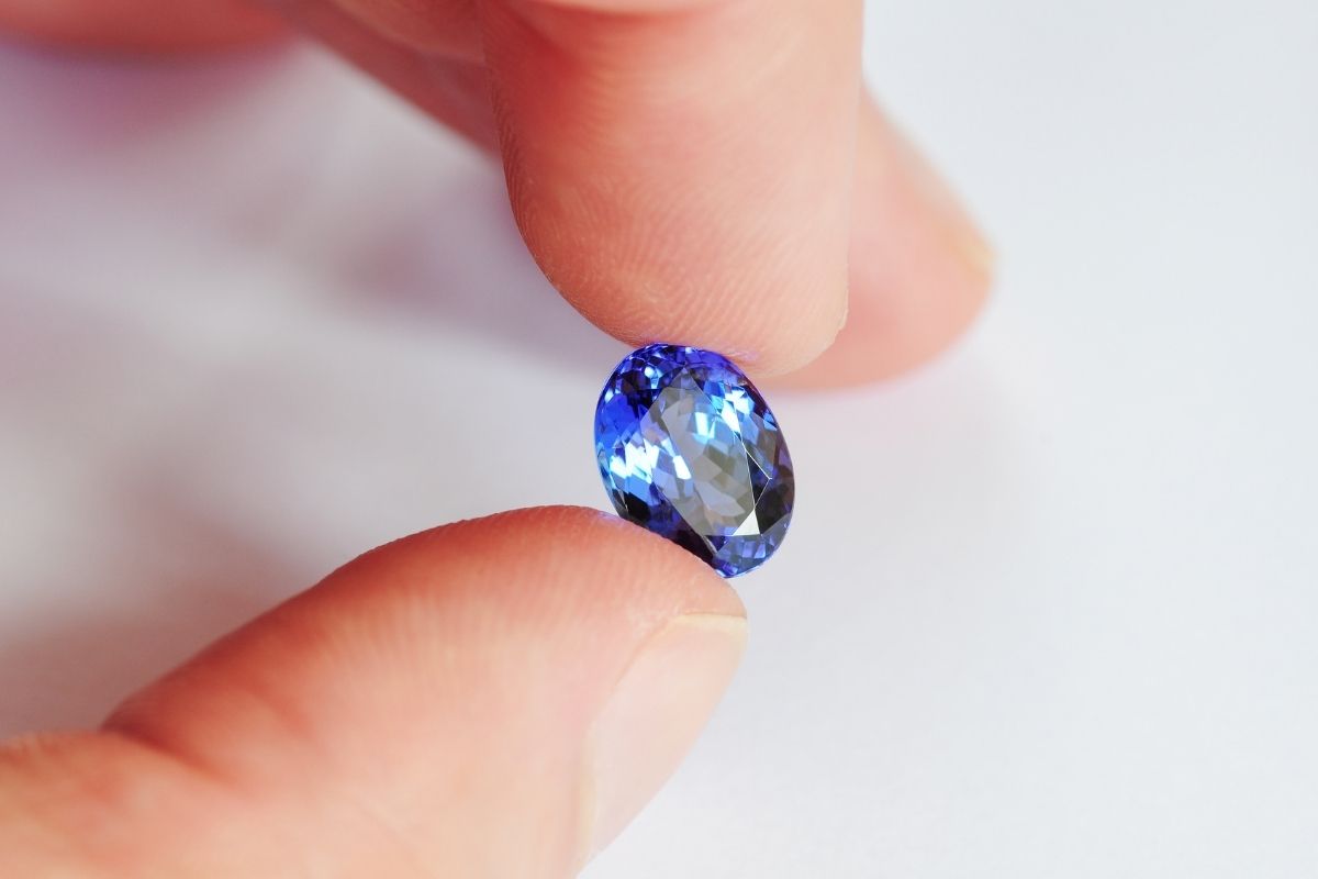 woman holding tanzanite stone between fingers