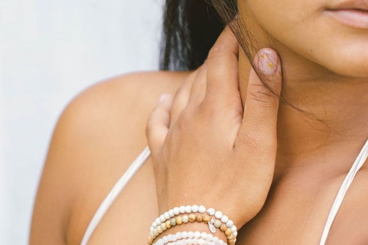 woman wearing gemstone bracelets holding neck