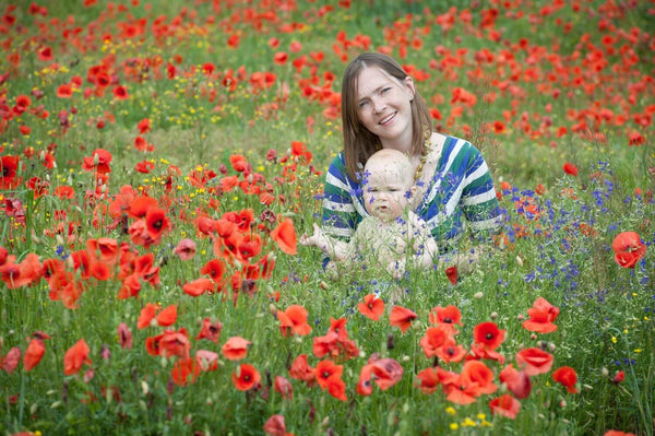 Woman and baby sat in field of poppies