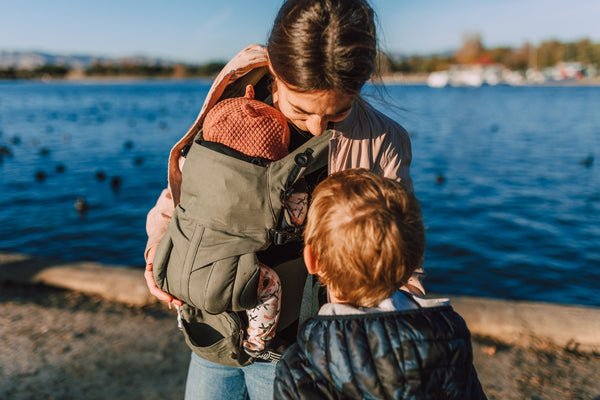 Mum-babywearing-smiling-down-at-toddler-walkign-next-to-her-bon-and-bear