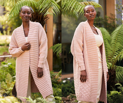 Two shots of a dark haired model wearing a long pink knitted duster in pale pink. She is holding the garment together in the front in the first picture. In the second picture she is turned to show the stitch work on the garment