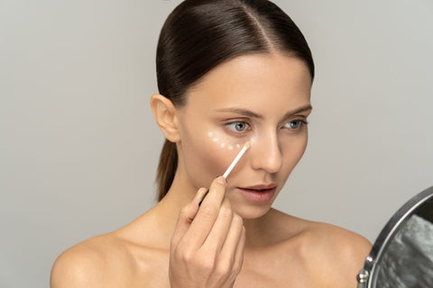 Woman applying eye cream in mirror