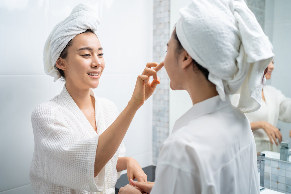 two women in robes applying skincare