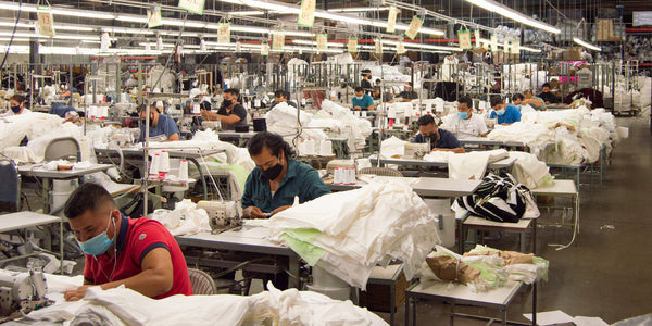 group of workers sitting behind sewing machines sewing new clothing at our LA factory