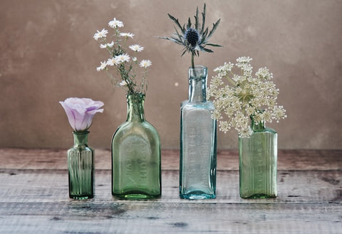 four glass bottles containing flowers