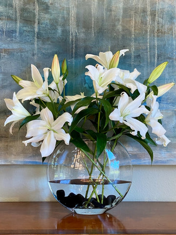 white lilies in a fish bowl vase
