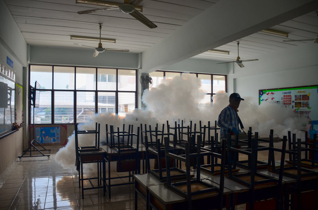 Man using sanitizing fogger machine in classroom. Invatech Italia