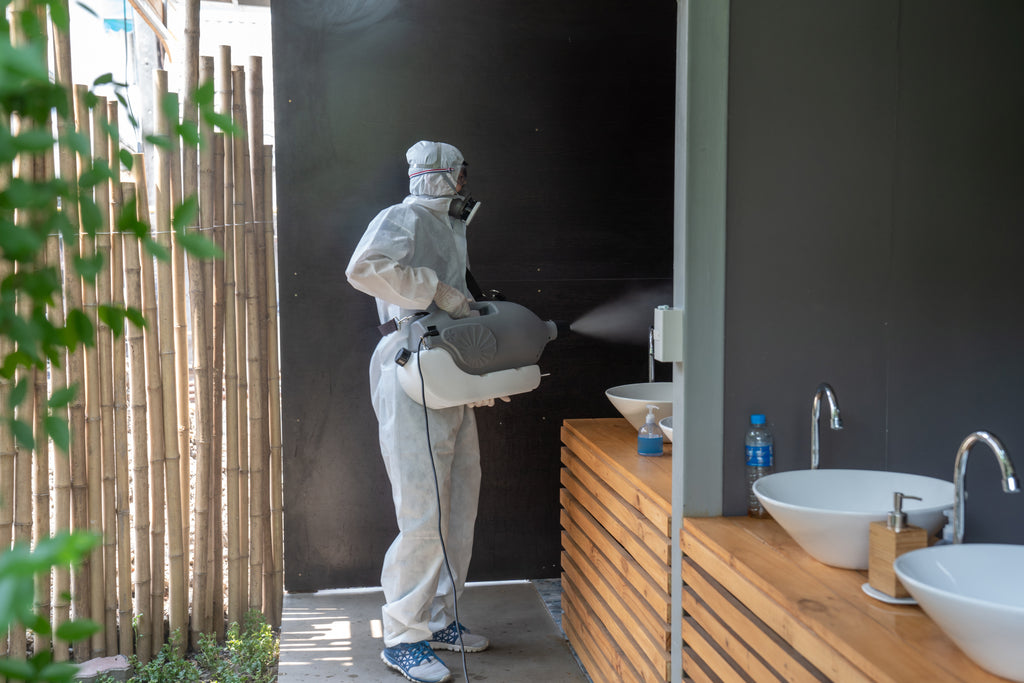 Professional using a ULV fogger sprayer to disinfect washroom. Invatech Italia