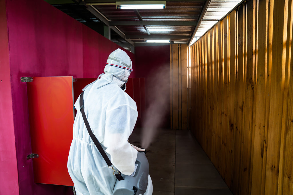 Professional in a protective suit using a fogger sprayer in room. Invatech Italia