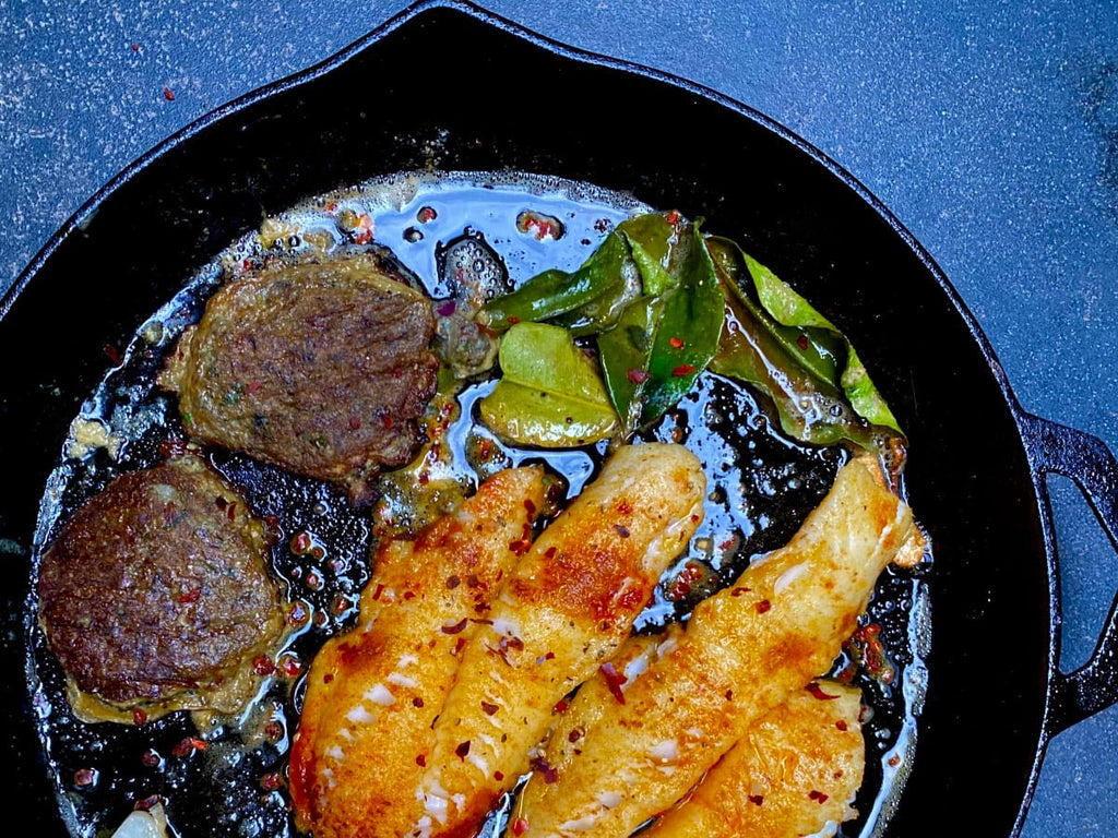 Cast iron pan with fritters and fish in it