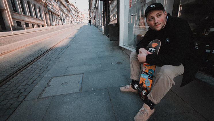 Man wearing vegan sneakers holding a skateboard in a street in the Portuguese city of Porto