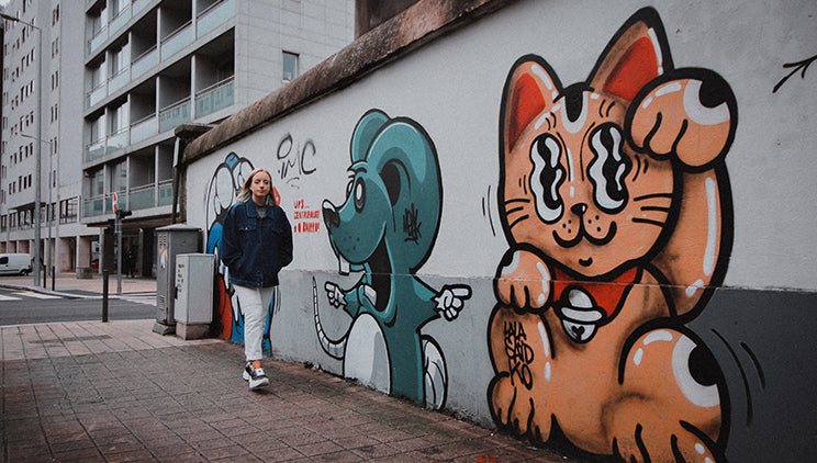 A woman walking past graffiti in Porto wearing chunky platform vegan sneakers made from trash.
