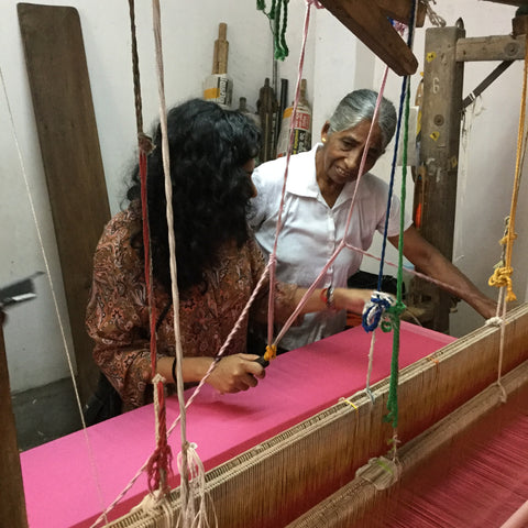 Being shown how to weave on a wooden handloom