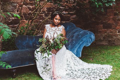 Black bride on a blue sofa with bouquet