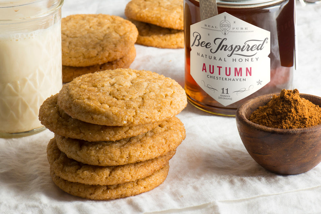 Honey Ginger Cookies on a white table next to a glass of milk and a jar of Bee Inspired Autumn Honey.