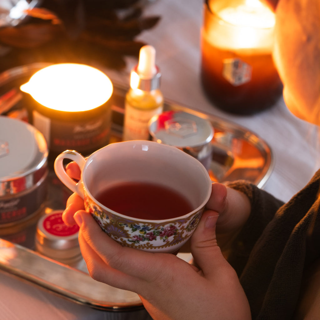 Woman holds mug of tea next to Rose Garden display