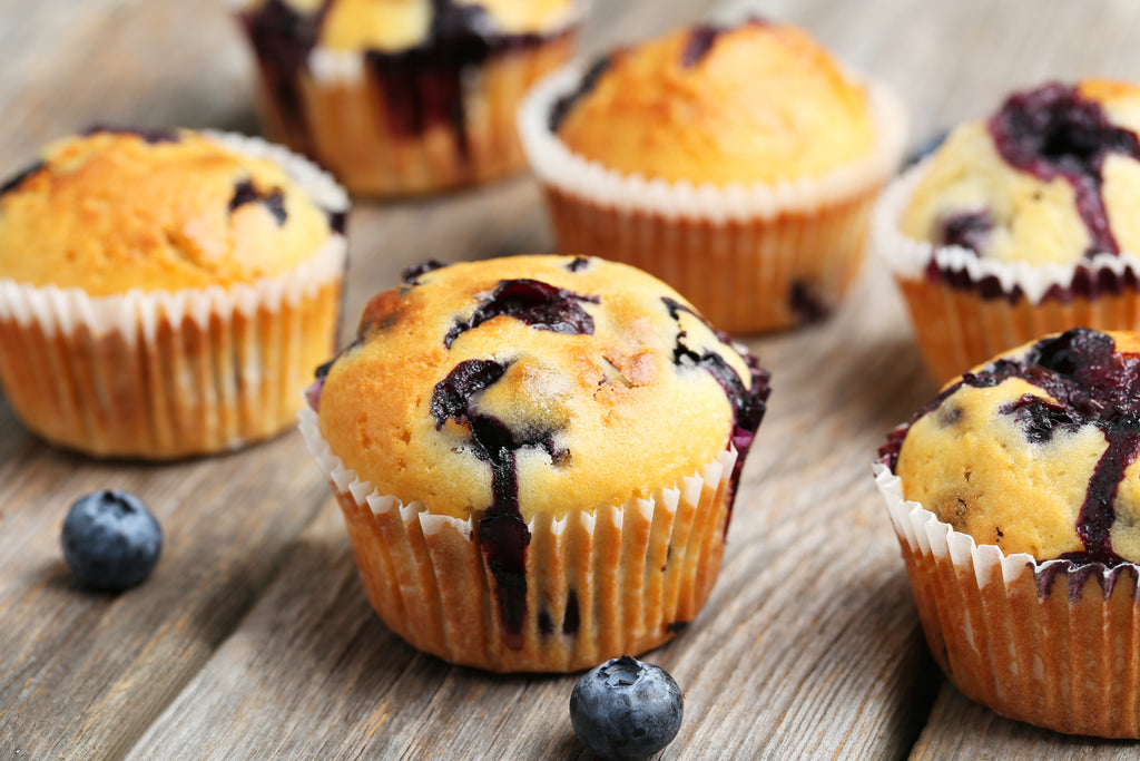 Blueberry muffins sitting on a wooden surface.