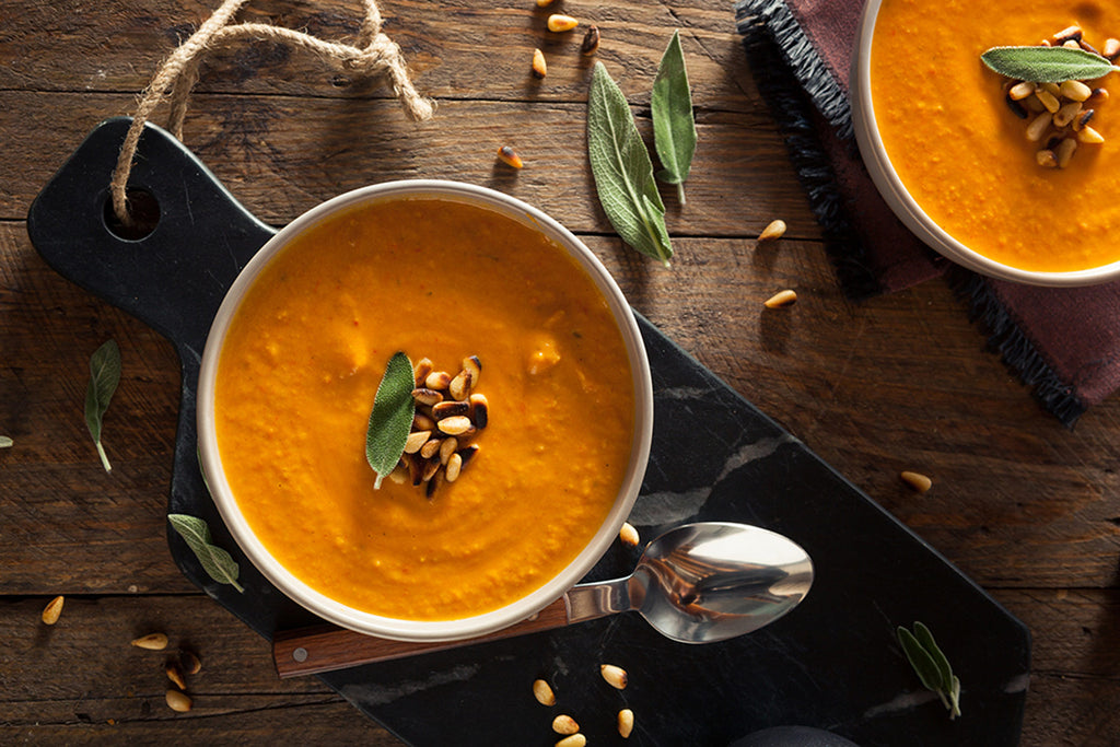 Two bowls of Carrot Ginger Soup by Bee Inspired on a wooden table