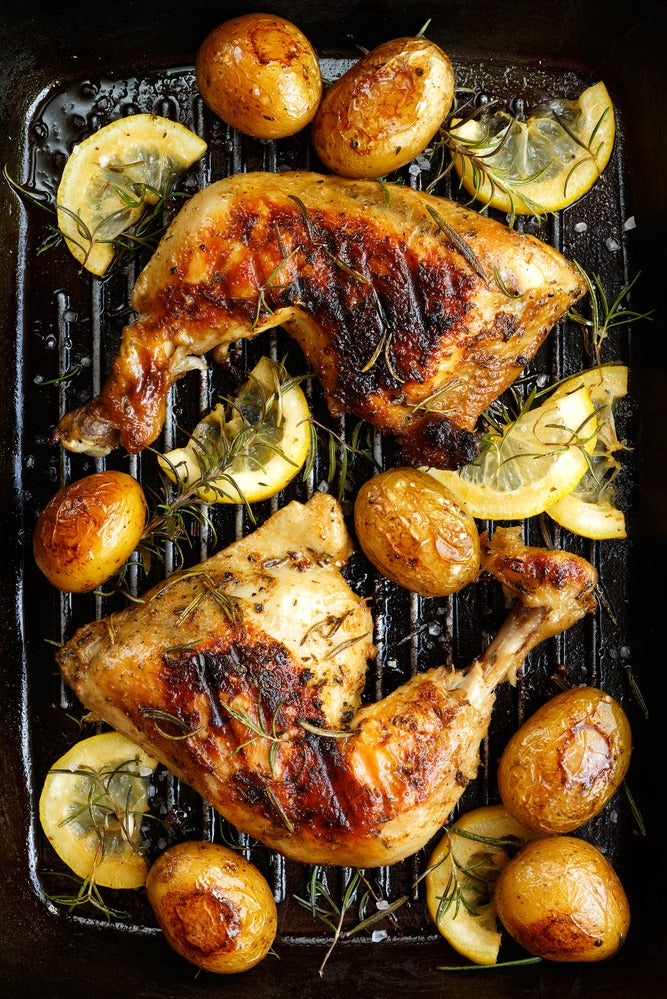 Chicken on a grill with potatoes and lemon slices