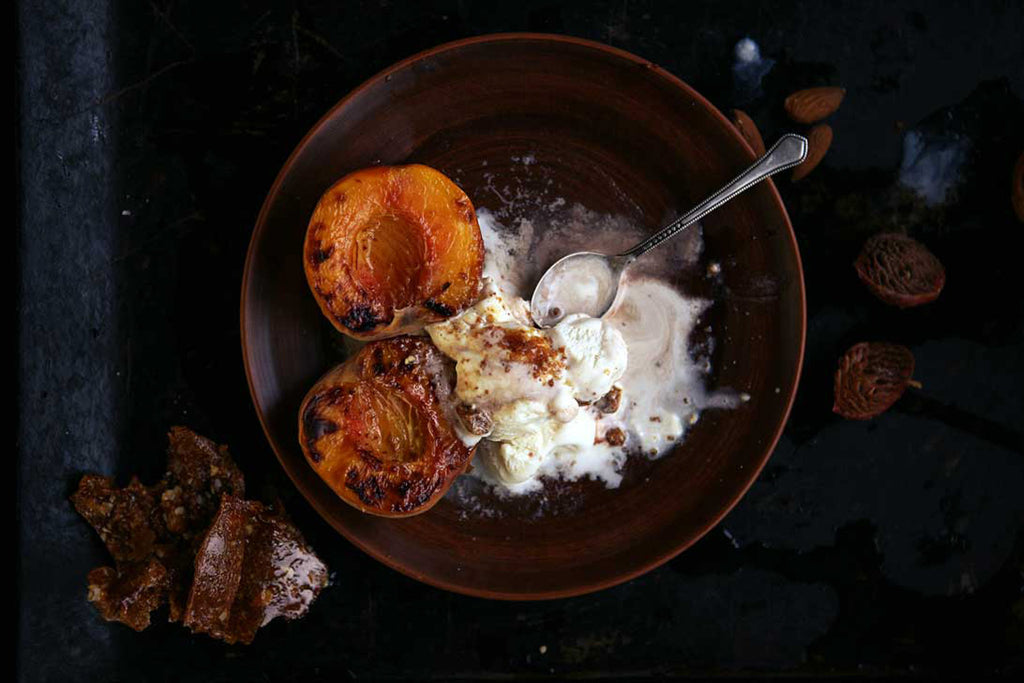 grilled peaches in a bowl served with vanilla ice cream