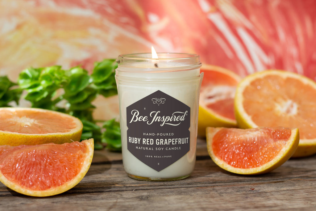 Ruby Red Grapefruit Jelly Jar Candle by Bee Inspired surrounded by fresh sliced grapefruit