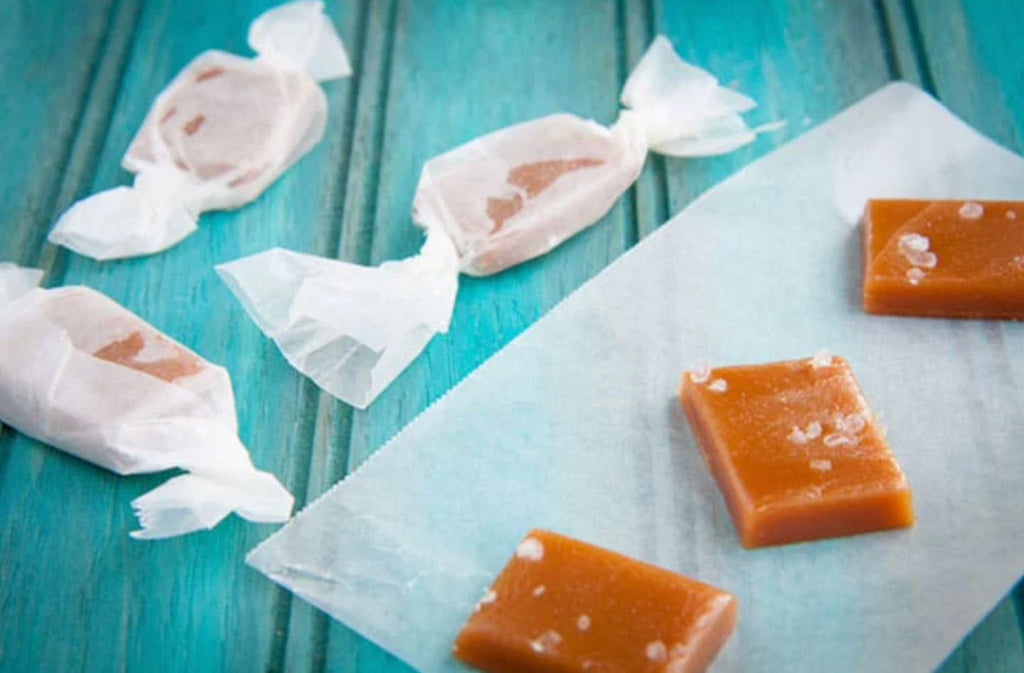 Three Salted Caramel Candies by Bee Inspired lined up next to each other on a piece of parchment paper