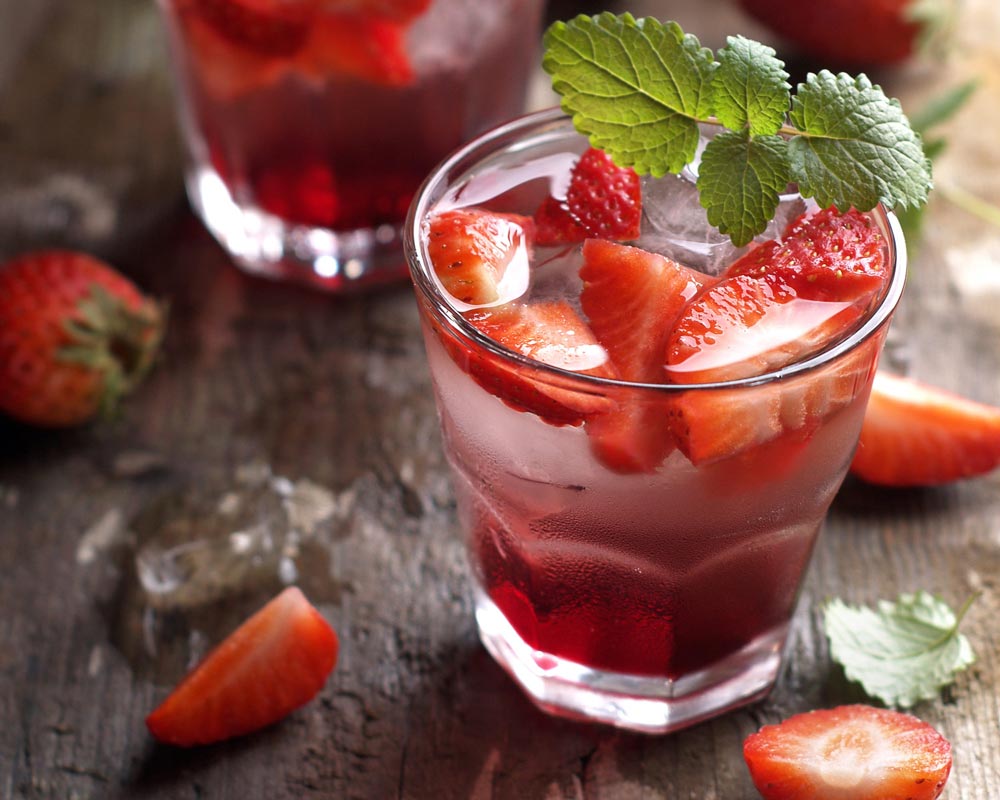Sparkling strawberry lemonade by Bee Inspired surrounded by strawberries