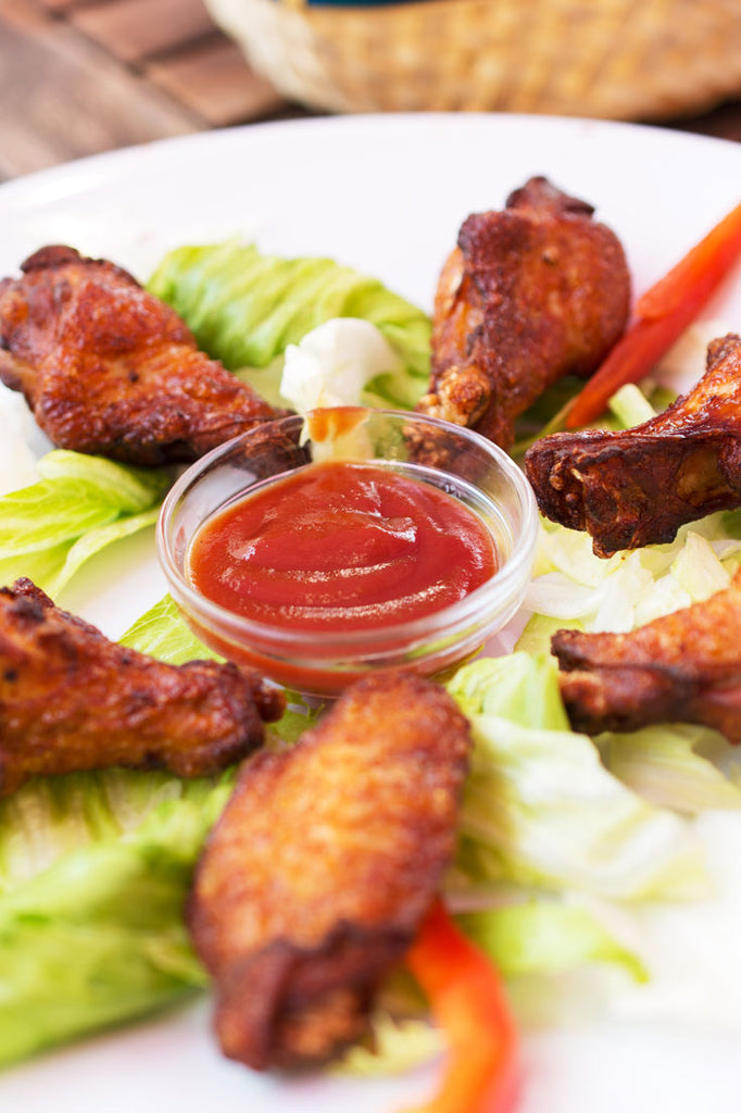 Thai Chicken Wings by Bee Inspired on a white plate with ketchup and lettuce