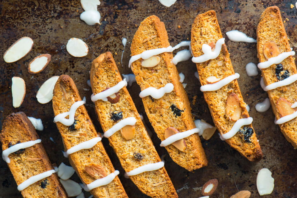 Cranberry Orange Biscotti on baking sheet close up with almond slivers and drizzle
