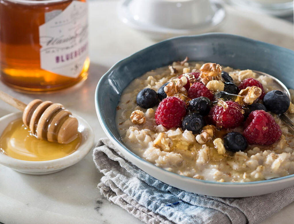 power porridge with fruit and honey on table with honey dipper in dish resting on blue napkin