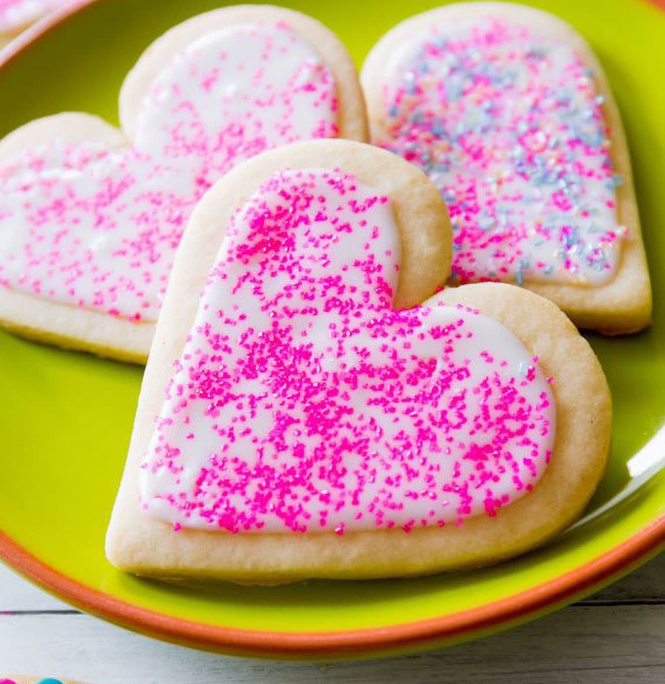 Sally's Baking Addiction Best Sugar Cookie Recipe pink heart sprinkled icing on sugar cookie on green plate