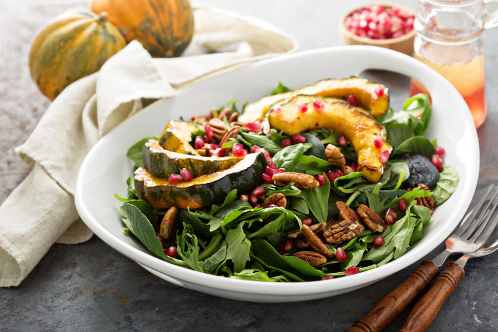 Acorn Squash Salad on table with forks and uncooked acorn squash and napikin and drink