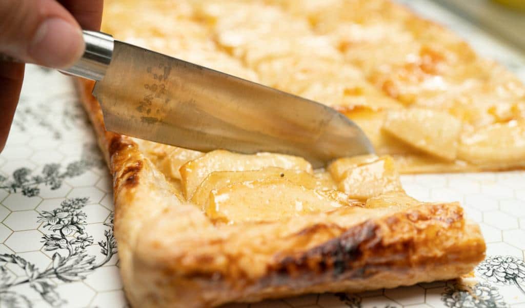 Slicing apple tart with knife