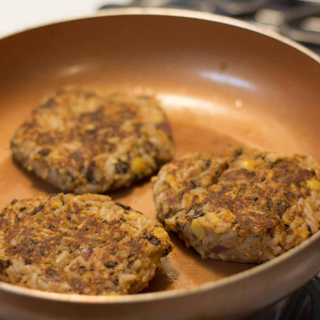 three black bean burgers with honey in pan