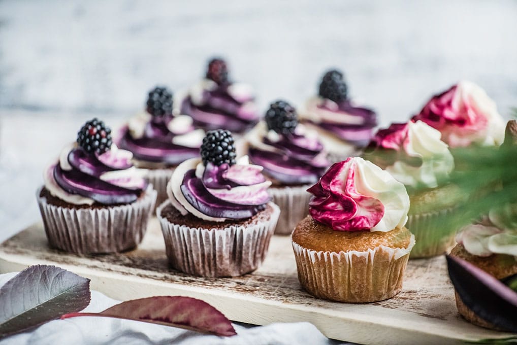 blackberry buttercream topped cupcakes on wooden tray