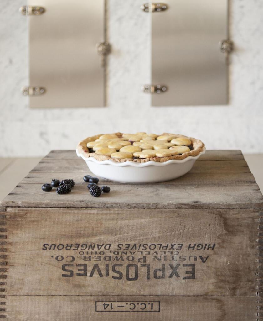 Fresh-Baked Pie on an explosives bin in white pie plate with a few fresh-picked blueberries and blackberries in front of and old-style ice chest.