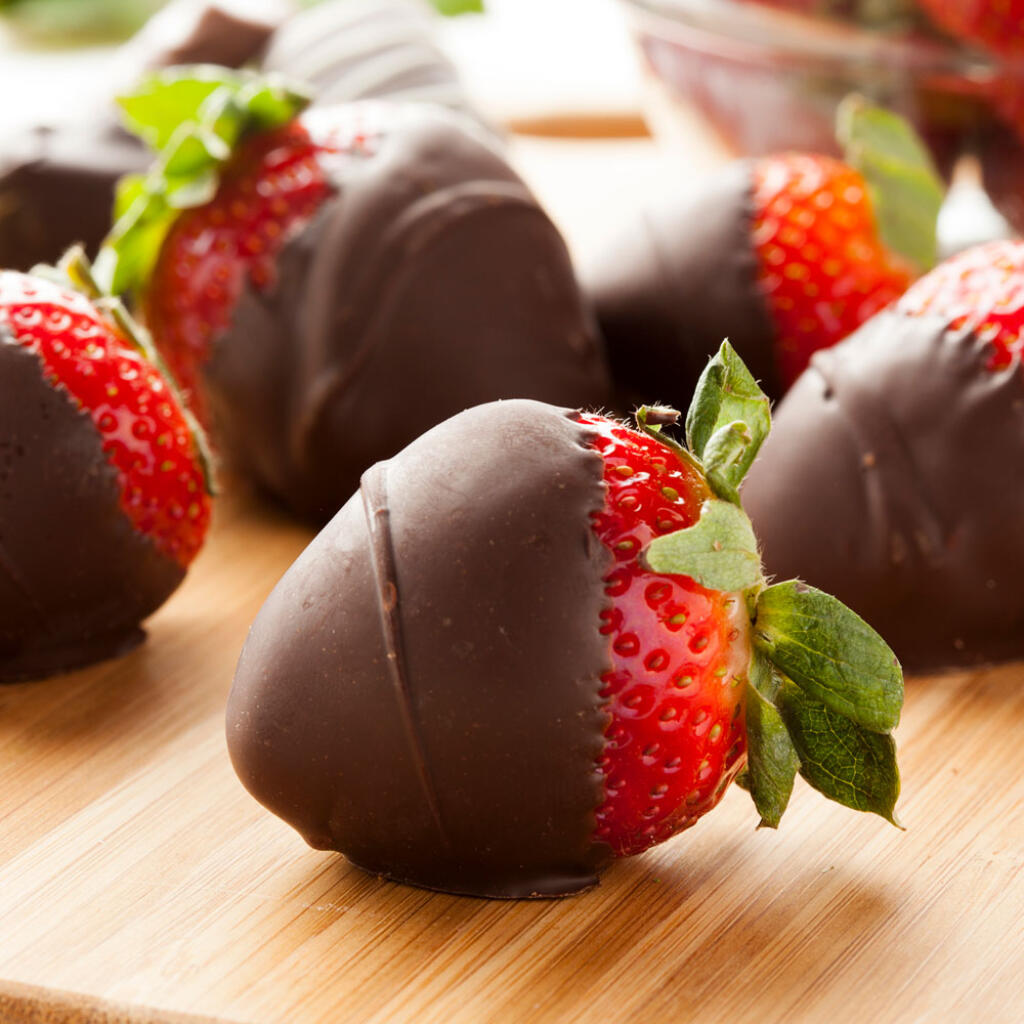 Chocolate dipped strawberries on wooden cutting board with stems showing