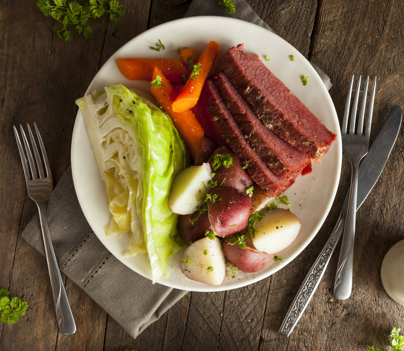 Glazed Corned beef and cabbag on dinner plate on dinner talble with napkin fork and knife